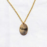 A 14k gold fill charm necklace engraved with art from Leslie and Sean's wedding invitation