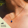 A woman wears a brilliant natural blue rock that's been polished and set in a 14k gold fill charm to wear on a chain. It's custom made, so you send the stone when ordering your jewelry.