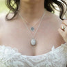 A bride wears a long pendant necklace made of white quartz
